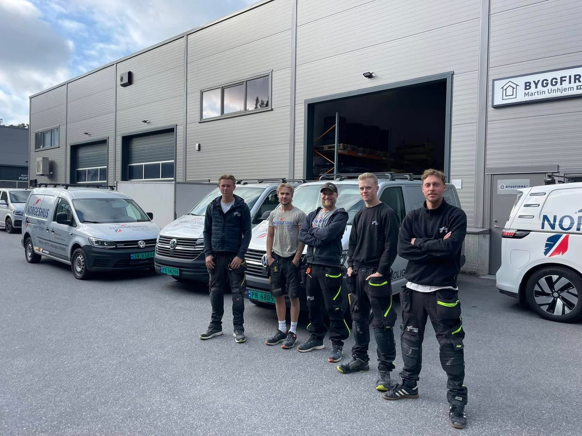 Fem av de ansatte i Byggfirma Martin Unhjem foran verkstedet og firmabilene